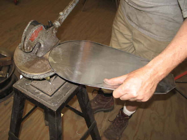 James rotates and guides the workpiece with his left hand as his right hand lowers the shear's lever.