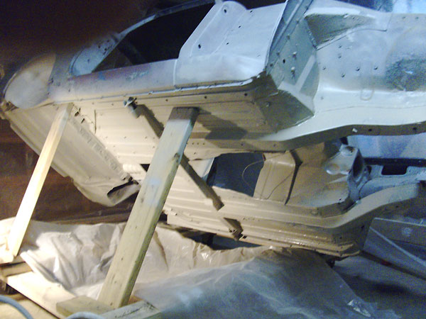 Stripped body was sandblasted and primed. Photo shows how car was hoisted and blocked to get to underside.