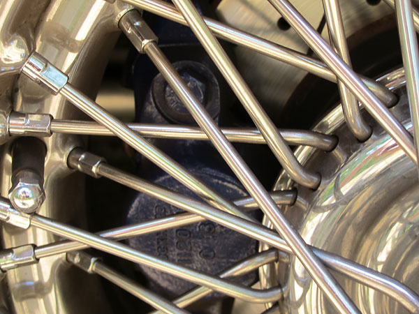 Drilled and slotted front brake rotors viewed through stainless steel spokes.